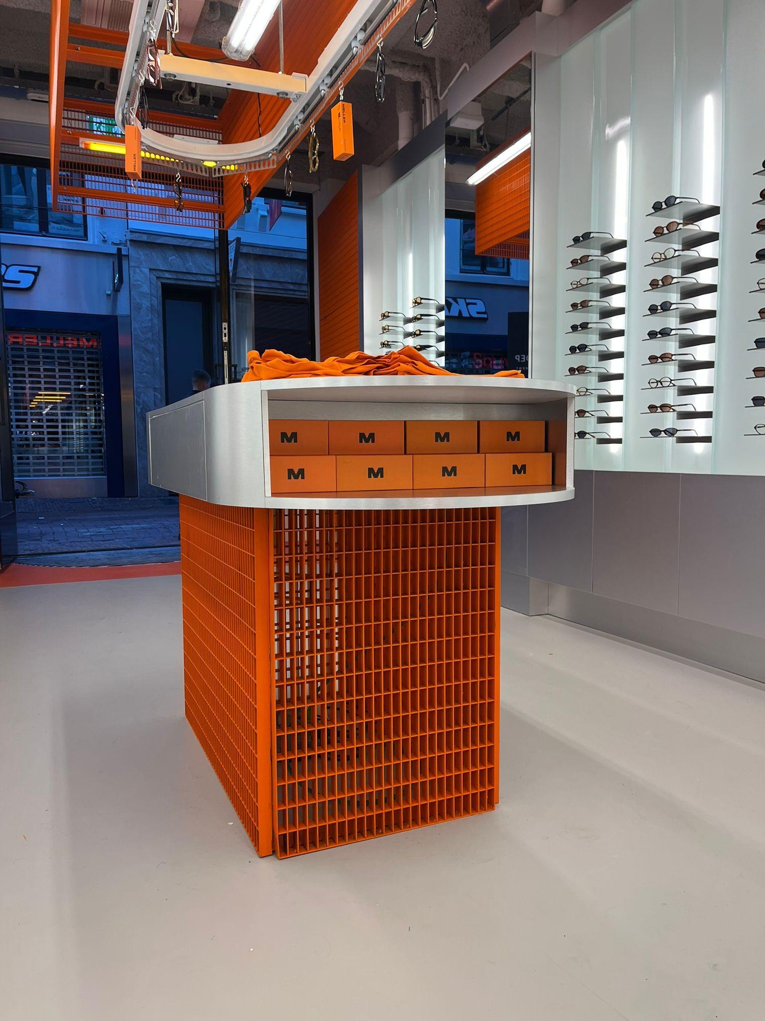 Oranje stalen mesh-onderstel van de kassa in de Meller-winkel, engineering door Previn Engineering